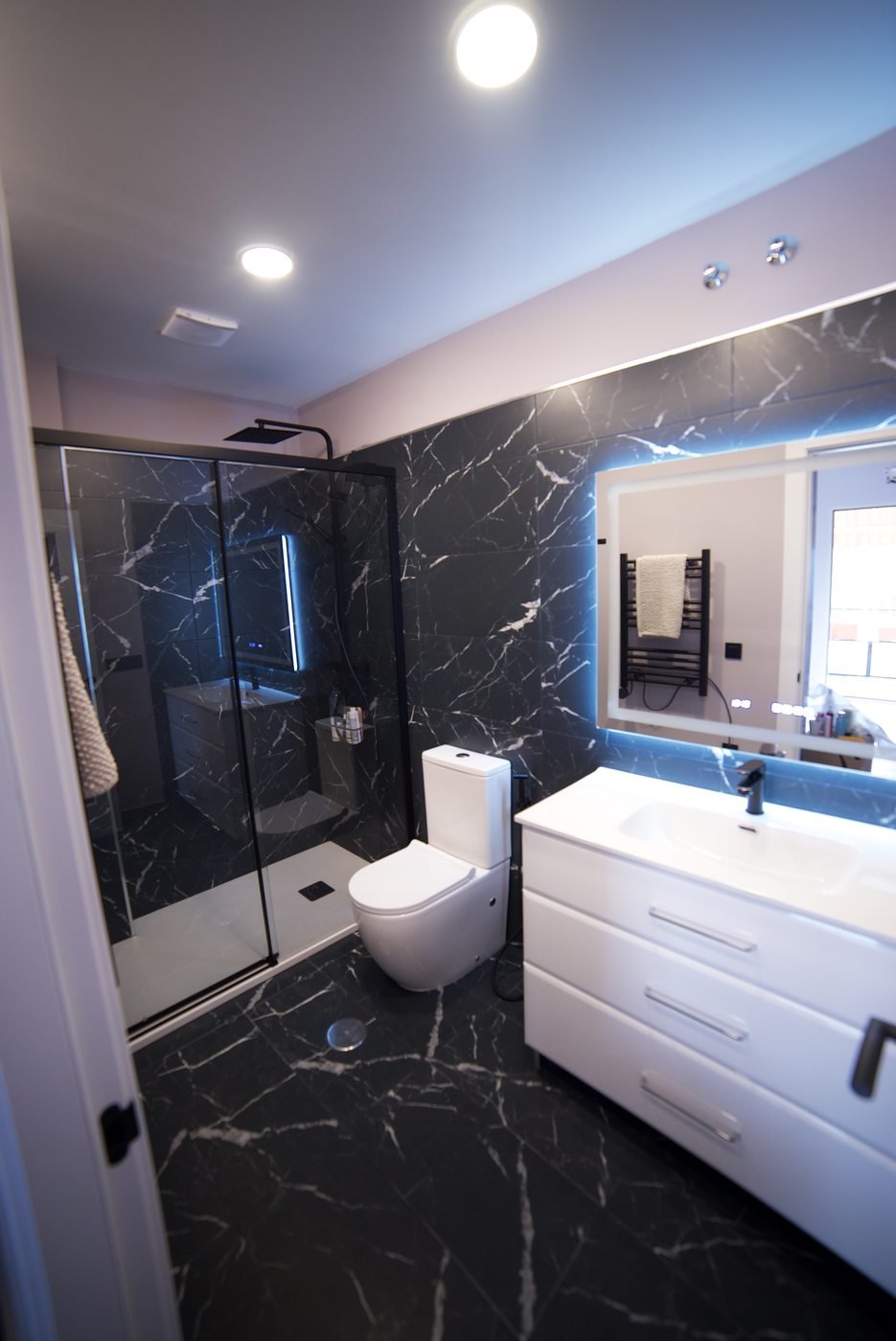 Baño terminado con mármol negro y ducha de obra